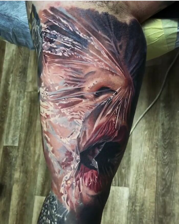 Quality tattoo with intricate details and colors, depicting a face wrapped in plastic for an unusual design effect.