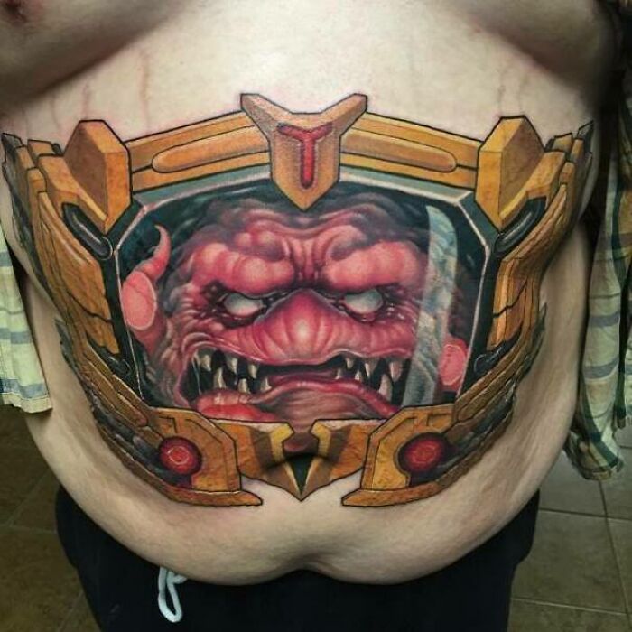 Tattoo of a detailed monster face on a stomach, showcasing impressive quality despite a questionable design choice.