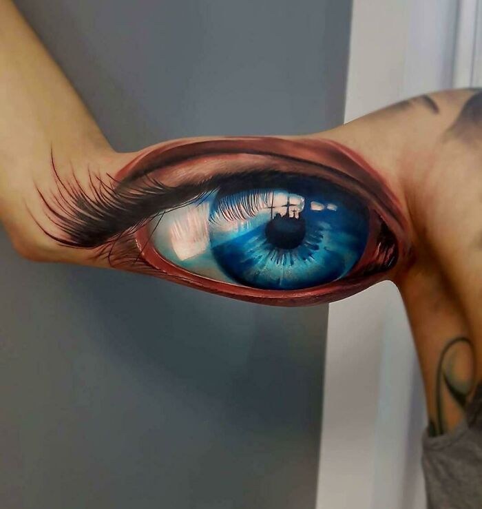 Realistic eye tattoo on arm, showcasing quality art but with a bizarre design choice.