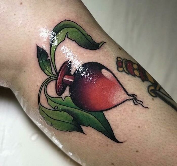 Colorful radish tattoo with lush leaves on forearm, demonstrating quality tattoo work with questionable design choice.