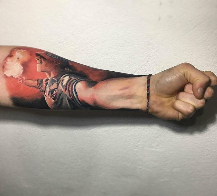 Arm with detailed tattoo design showing a person holding a flare, but the quality of the tattoo is questionable.