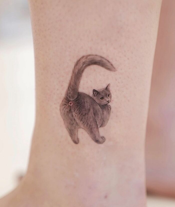 Tattoo of a cat on a leg, showcasing quality art with a humorous and odd design choice.