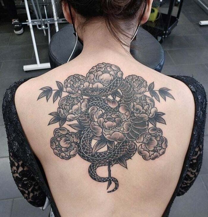 Back tattoo featuring a snake intertwined with peonies, showcasing a trippy tattoo design.