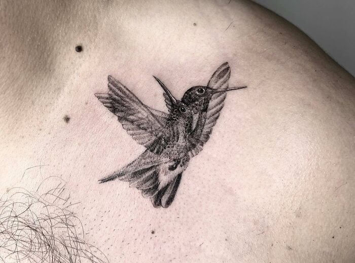 Trippy blurred bird tattoo on a man's chest, featuring a detailed avian design.