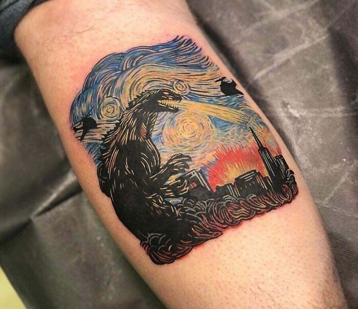 Trippy leg tattoo of Godzilla with Starry Night backdrop, featuring vibrant colors and city skyline.
