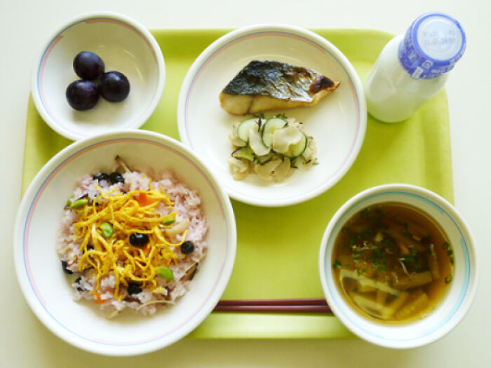 Plate with soup, fish, vegetables, rice and fruit with milk