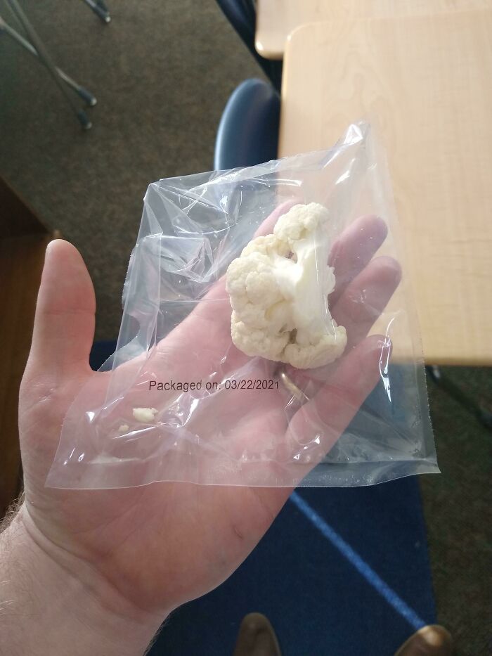 Person holding Cauliflower in plastic wrap