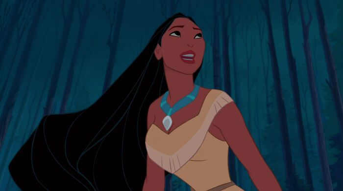 Female cartoon character standing in a forest, showcasing strength and confidence with long flowing hair and a blue necklace.