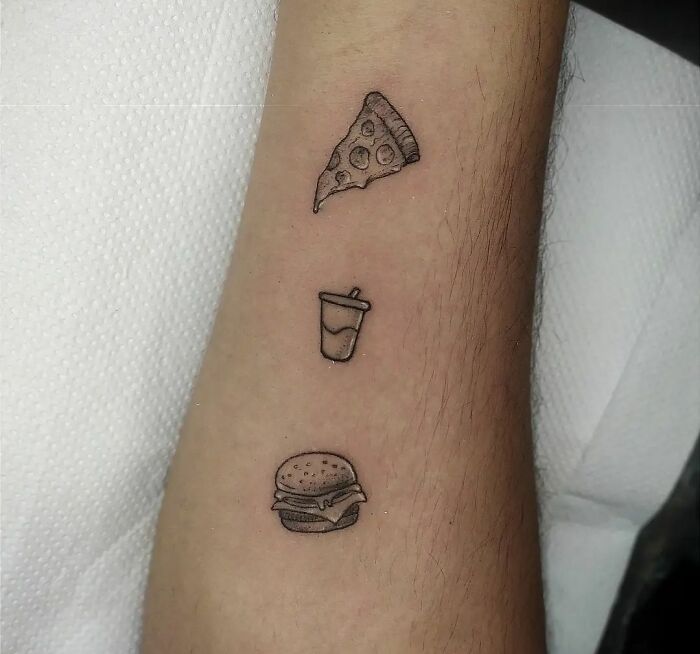 Minimal tattoo designs of pizza slice, drink, and burger on forearm.