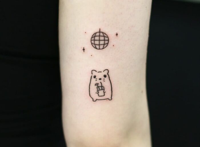 Minimal tattoo design featuring a cute bear with a drink and a small globe with stars.