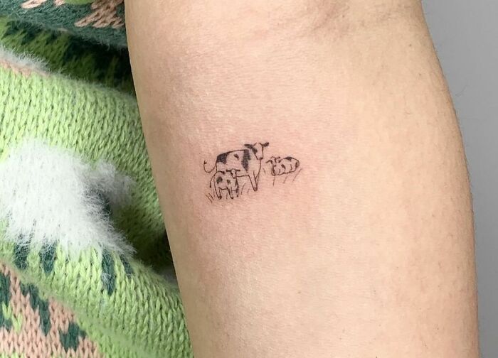 Minimal tattoo design on arm featuring a small cow family, showcasing intricate and detailed ink work.