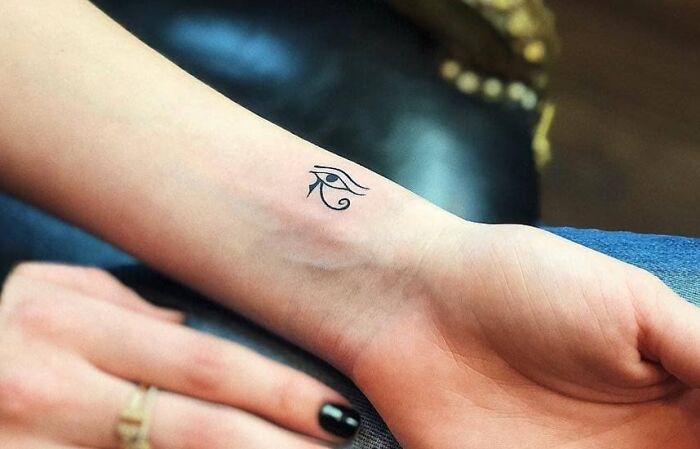 Minimal tattoo design of Eye of Horus on a person's inner wrist, showcasing detailed line work.