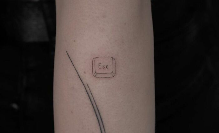 Minimal tattoo featuring an "Esc" key on a person's arm with a simple line design in a minimalist style.