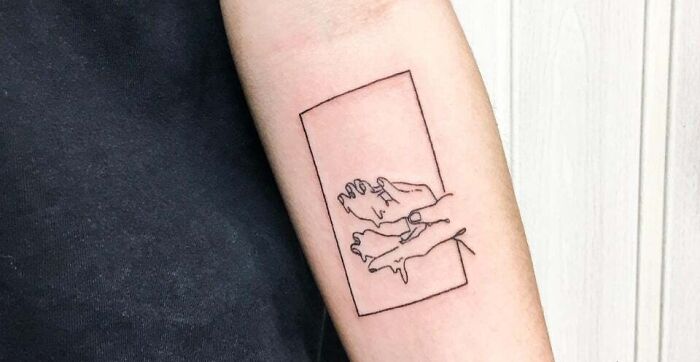Minimal tattoo design of outlined hands within a rectangle on a person's forearm.