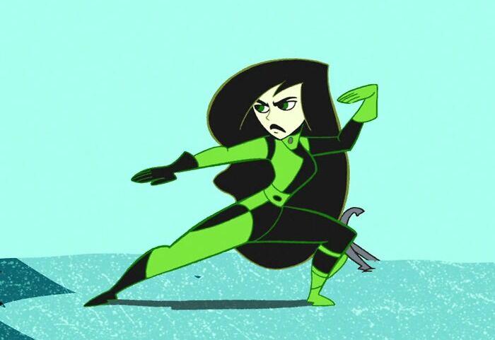 A strong female cartoon character in action pose, wearing a black and green outfit.
