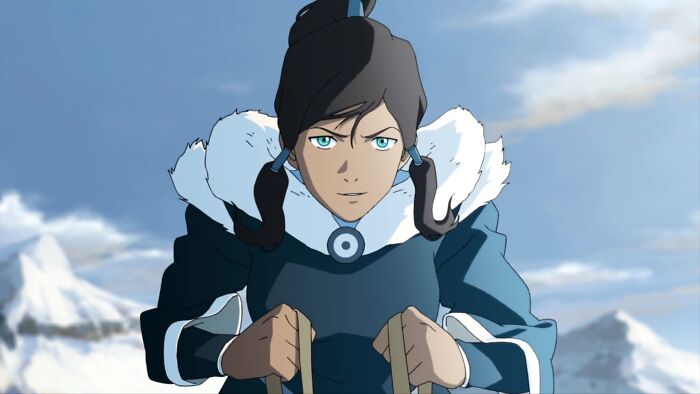Female cartoon character with determined expression, wearing a fur-lined blue outfit against a snowy mountain backdrop.