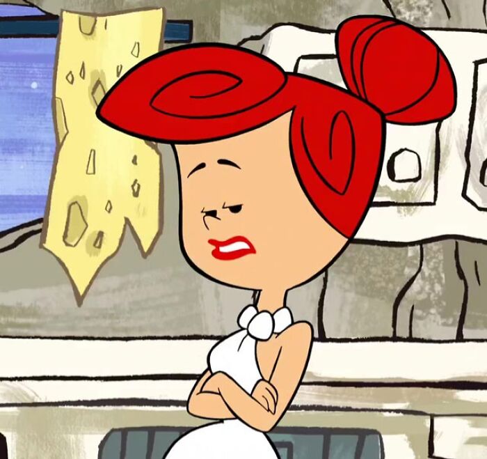 Female cartoon character with red hair, showcasing confidence and strength in a prehistoric-style setting.