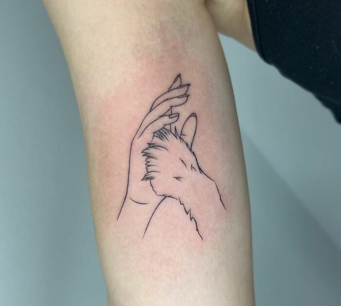 Pet tattoo featuring a hand and paw intertwined, symbolizing the bond between humans and their adorable furry companions.