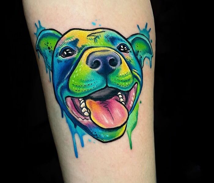 Vibrant pet tattoo of a smiling dog with multicolored fur, capturing adorable expression on skin.