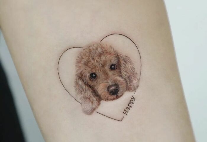 Heart-shaped pet tattoo with fluffy dog and "Happy" text, celebrating adorable pet tattoos.