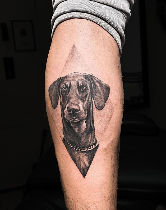 Pet tattoo of a dog's face on a person's leg, showcasing detailed artistry to immortalize their beloved companion.