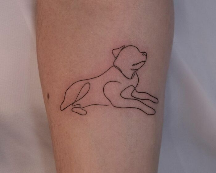 Single-line tattoo of a dog in fine-line style on a person's arm.