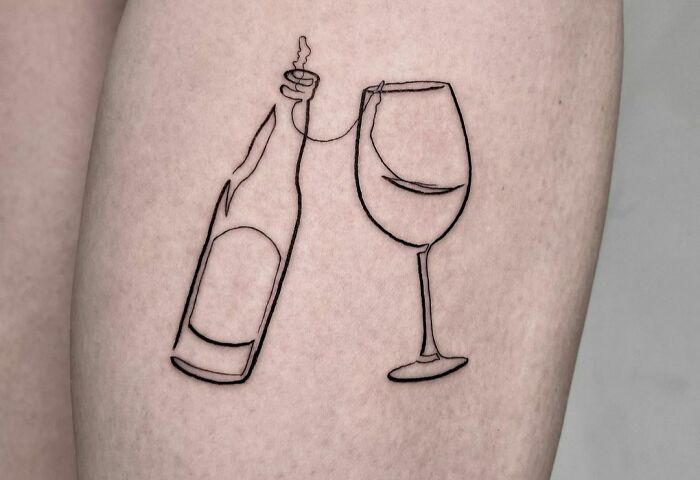 Fine-line tattoo of a wine bottle and glass, drawn with a single line on skin.