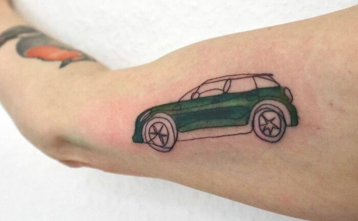 Fine-line tattoo of a green car on an arm.