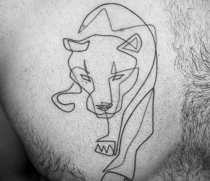 Fine-line perfection: a delicate single-line tattoo of a stylized lion on a person's skin.