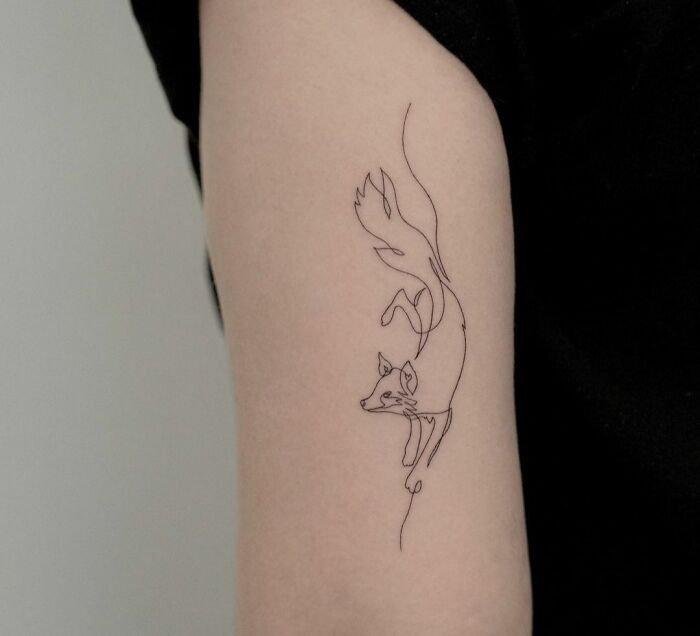 Fine-line single-line fox tattoo on an arm, showcasing minimalist tattoo design.
