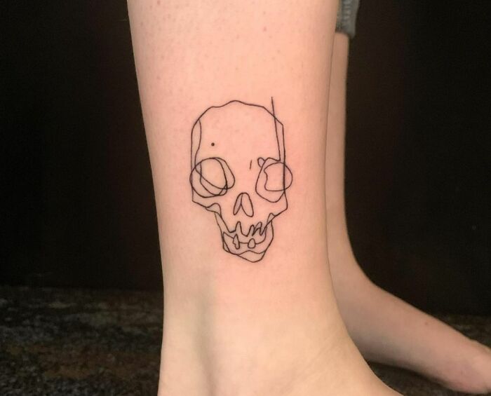 Single-line tattoo of a skull on the ankle, showcasing fine-line perfection.