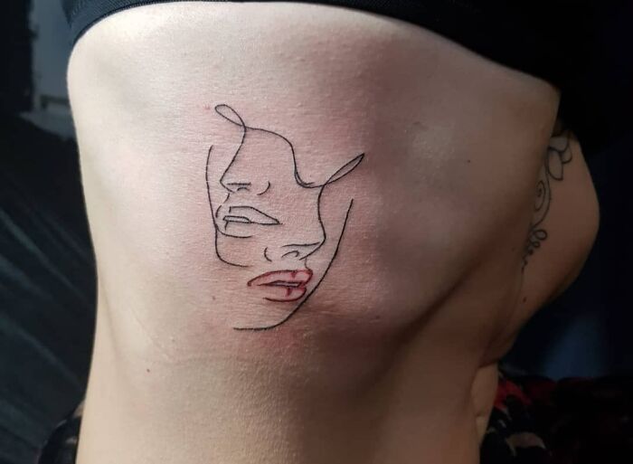 Fine-line single-line tattoo of two abstract faces on the side of the torso.