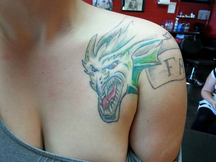 Funny dragon shoulder tattoo with vibrant colors and whimsical design.