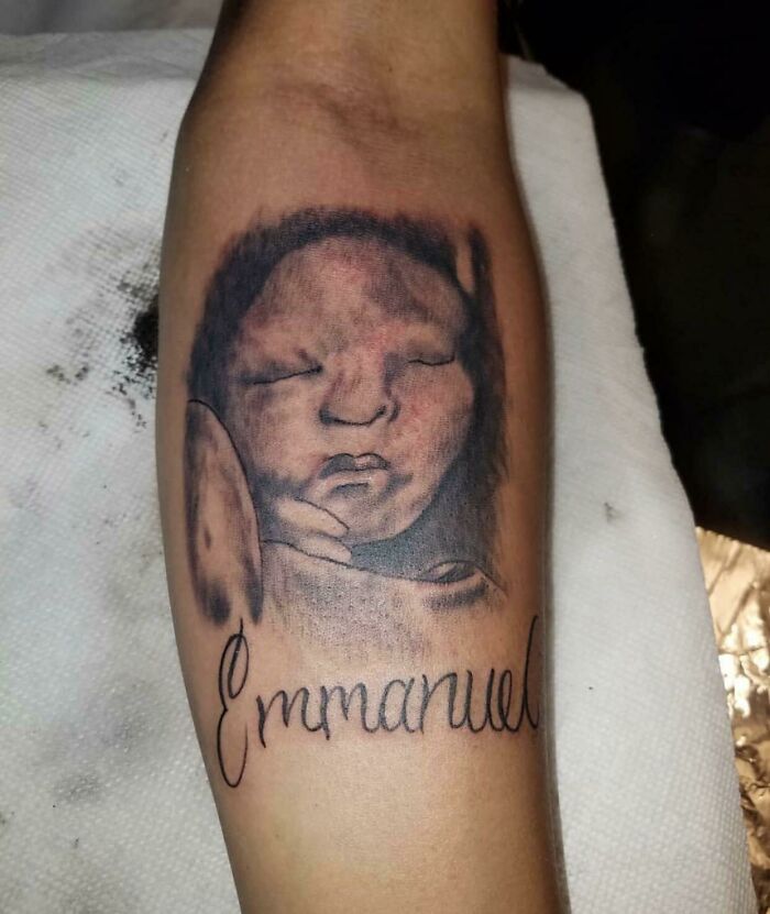 Tattoo of a baby's face with the name "Emmanuel" on an arm, featuring funny tattoo art.