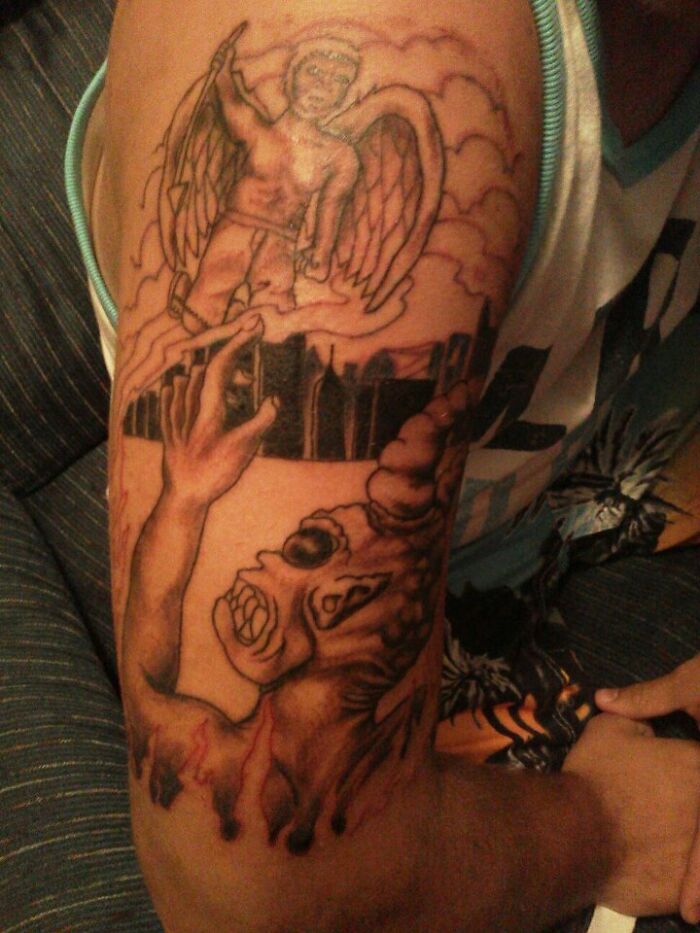 Funny arm tattoo featuring an angel and a comical demon in a surreal scene.
