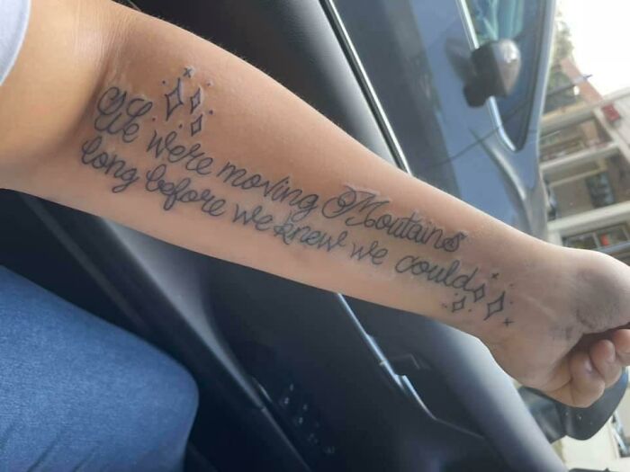 Funny tattoo with cursive text on an arm saying "We were moving mountains long before we knew we could."