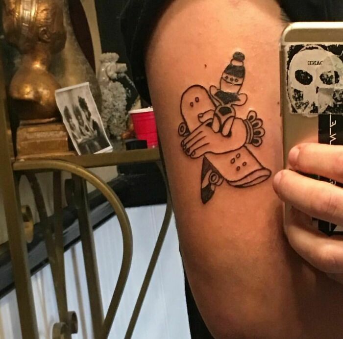 Funny tattoo of a cartoon character holding a skateboard on someone's arm.