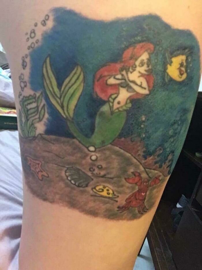 Funny tattoo of a cartoon mermaid and fish under the sea, showcasing humor and vibrant colors.