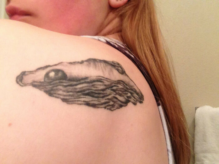 A funny tattoo of an eye on a woman's shoulder, resembling a landscape with a pearl.