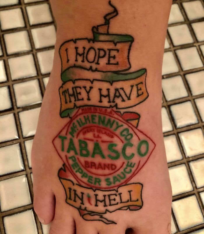 Funny tattoo of a Tabasco sauce label on a foot, surrounded by humorous text.