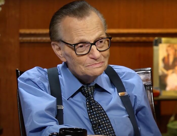 Larry King wearing a blue shirt and tie, often featured among famous people who got married multiple times.