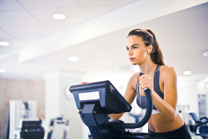 Woman with ear phones using gym equipment 