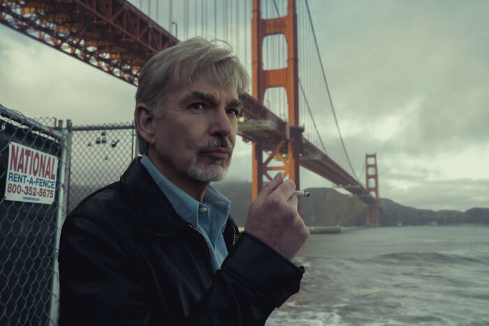 Billy Bob Thornton smoking near the Golden Gate Bridge in Goliath, representing famous people who got married multiple times.