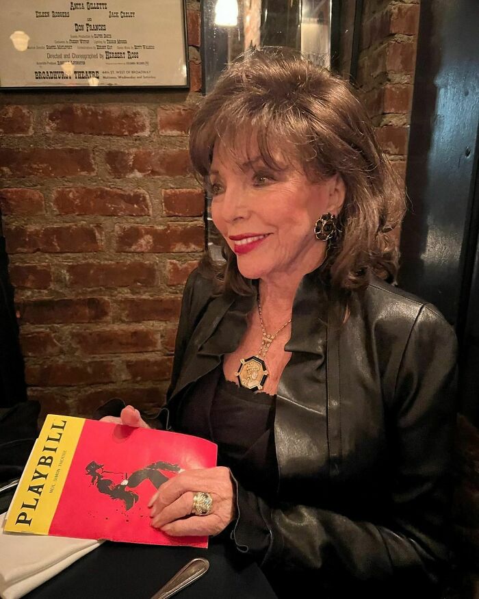 Joan Collins wearing a black leather jacket, holding a Playbill, featured among famous people married multiple times.