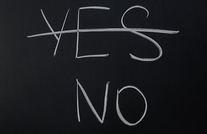 Chalkboard with the word yes crossed out and the word no written below, symbolizing texting games choices.