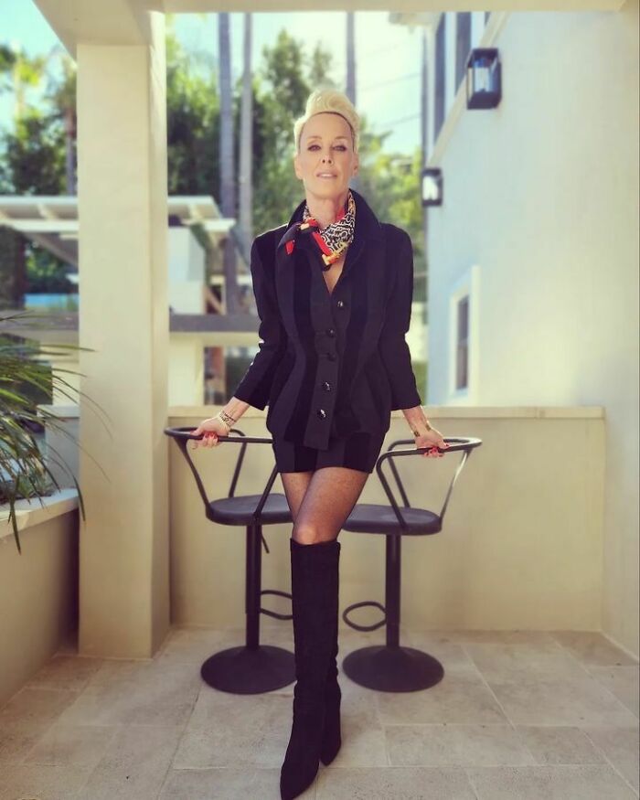 Brigitte Nielsen wearing a black jacket and boots, posing outdoors among famous people who got married multiple times.