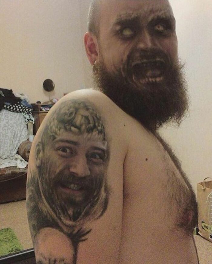 Person with a beard showcasing a tattoo of a face on their shoulder, highlighting terrible tattoos.