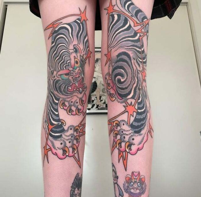 Two legs adorned with complex, swirling trippy tattoos featuring bold colors and intricate designs.