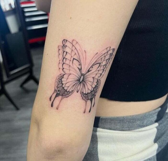 Trippy tattoo of a butterfly with dripping edges on a person's arm, showcasing a surreal design.