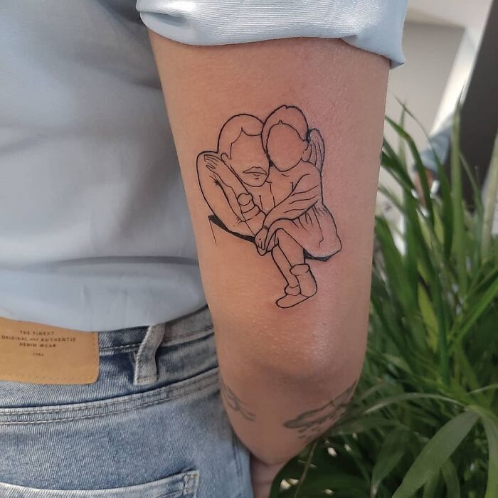 Mom tattoo depicting mother and child embracing, symbolizing their bond on a person's arm.